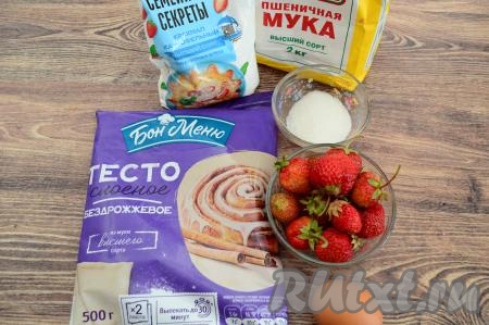 Подготовить продукты для приготовления конвертиков с клубникой из слоёного теста. Для этой выпечки подойдёт и бездрожжевое слоёное тесто (я его и купила), и дрожжевое слоёное тесто. Его нужно будет заранее вынуть из морозилки и оставить размораживаться при комнатной температуре. Клубнику можно взять как свежую, так и замороженную. Свежую клубнику нужно будет отделить от чашелистиков, промыть водой и обсушить, разложив ягодки на бумажном полотенце. Если же клубника замороженная и на ней нет большого количества льда, тогда её нужно будет разморозить настолько, чтобы её можно было нарезать на части.