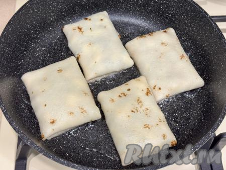В сковороду влить растительное масло, разогреть, выложить блины с начинкой. 