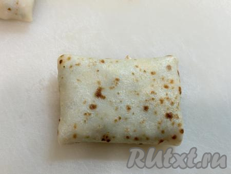 И, начиная со стороны с луково-яичной начинкой, завернуть блин в прямоугольный конвертик. 