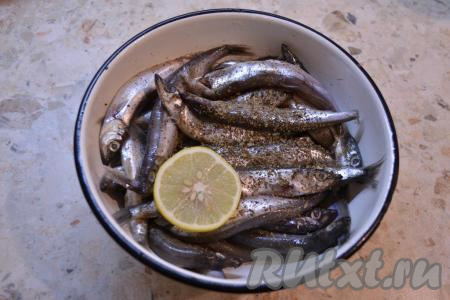 Сбрызнуть мойву лимонным соком, посыпать черным молотым перцем и сушеным базиликом, посолить, перемешать. Оставить рыбу промариноваться на 30 минут.