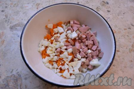 В салат к картофелю и моркови добавить рубленные вареные яйца и нарезанную небольшими кубиками колбасу.