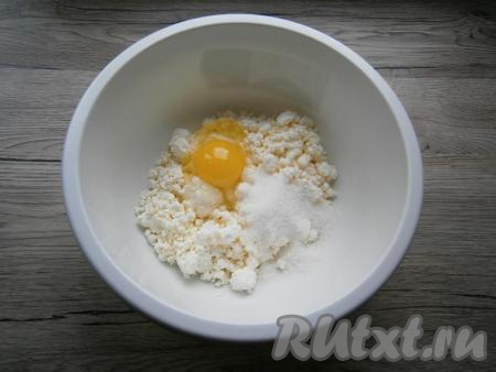 Для приготовления теста к творогу добавить сырое яйцо, всыпать 2 столовые ложки сахара, соль и соду.