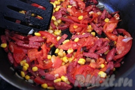 Колбасу, лук и помидор нарезать дольками, добавить кукурузу и обжарить всё вместе на небольшом количестве растительного масла. Специи и зелень - по вкусу.