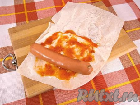 Размазать кетчуп поверх майонеза. Ближе к краю поверх кетчупа разместить сосиску.&nbsp;