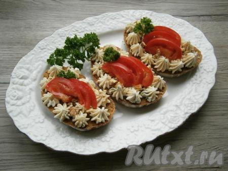 Сверху бутерброды посыпать рубленными грецкими орехами, выложить по 3 дольки свежего помидора, украсить веточками петрушки.