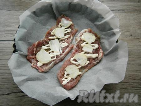 Смазать мясо немного майонезом, выложить очищенный и тонко нарезанный репчатый лук.