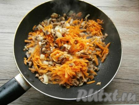 Обжаривать грибы с луком на среднем огне, помешивая, около 5-7 минут, после чего добавить в сковороду натертую на крупной терке очищенную морковь.