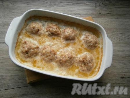 Форму с куриными тефтелями в сметанном соусе накрыть фольгой и отправить в разогретую до 180 градусов духовку на 30 минут, после чего фольгу убрать и запекать еще 10 минут.