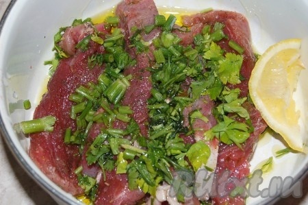 Сложить куски мяса в миску, добавить нарезанную зелень, оливковое масло. Перемешать.