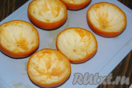 Для апельсиновых чашечек лучше использовать мелкие апельсины. Апельсины вымыть, разрезать на две части и с помощью ложки удалить мякоть. Выложить апельсиновые чашки в силиконовые формочки для кексов.