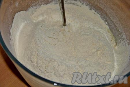 Всыпать 400 грамм муки и всю соль. Сначала перемешивать тесто столовой ложкой, а когда тесто начнёт собираться в ком, продолжить замес руками.
