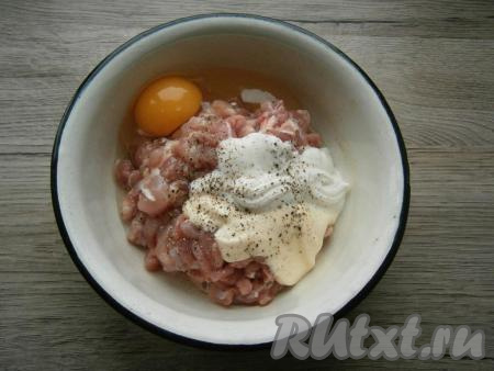 Мясо курицы нарезать острым ножом на очень мелкие кусочки. Добавить к мясу сырое яйцо, майонез и сметану, посолить и поперчить, перемешать.