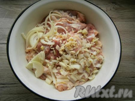 Чеснок и лук очистить. Сложить куриное мясо в миску, добавить нарезанный тонкими полукольцами репчатый лук и измельченный чеснок.