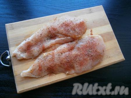 Разрезать куриное филе вдоль на 2 части потоньше. Посыпать мясо специями, солью, черным молотым перцем и паприкой.