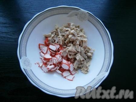 Отварное куриное мясо нарезать кусочками. К куриному мясу добавить нарезанные кружочками крабовые палочки.