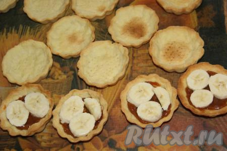 Бананы очистить и нарезать на кружочки. Выложить по 2-3 кусочка банана поверх сгущёнки в каждую корзиночку.