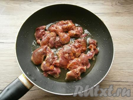 Разогреть на сковороде растительное масло, выложить печенку, посолить ее, посыпать специями для курицы и черным молотым перцем.