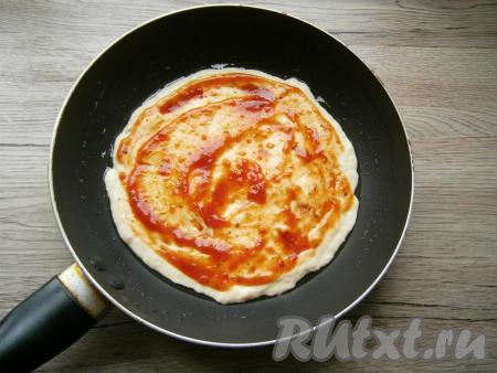 Холодную сковороду смазать растительным маслом. Выложить тесто и разровнять его по дну сковороды. Смазать тесто томатным соусом.