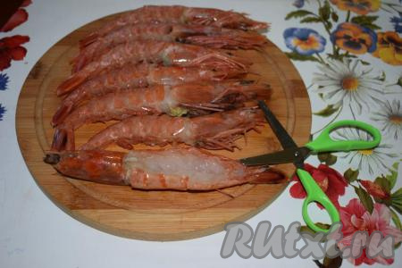 Лангустины размораживаем при комнатной температуре и промываем под холодной водой. Далее берем каждого лангустина, разрезаем хвостовую часть при помощи ножниц, начиная от головы к хвосту, затем удаляем кишку, обрезаем мелкие лапки и промываем.