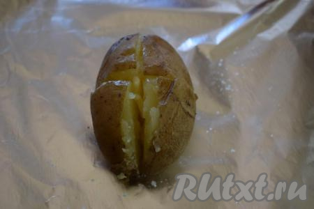 Картофель охлаждаем до такого состояния, чтобы его можно было держать в руках и не обжечься. Берем фольгу, нам понадобится столько кусочков фольги, сколько картофелин. Кладем одну картошину на середину куска фольги. На руки наливаем несколько капель растительного масла и обтираем картофелину со всех сторон маслом. Делаем крестообразный разрез на картофелине (как на фото).