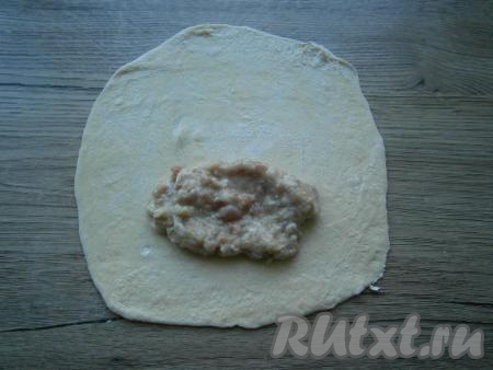 Подсыпая на стол муку, раскатать каждую часть теста в тонкую лепешку. Ближе к краю лепешки выложить 1-2 столовые ложки фарша.