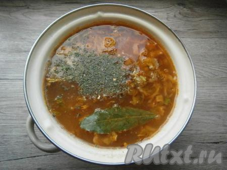 Когда картофель сварится, добавить в кастрюлю тушеную капусту с овощами со сковороды, приправу, специи, лавровый лист и измельченный чеснок, довести до кипения и уменьшить огонь.
