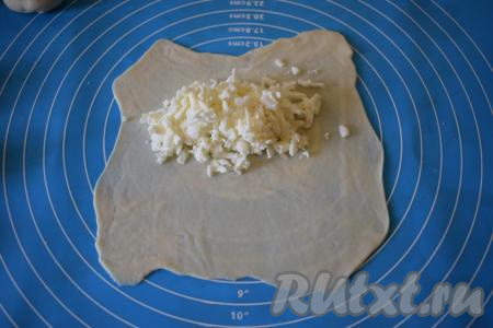 Присыпаем мукой поверхность, на которой будем работать с тестом. Каждую часть теста раскатываем в тонкий круг диаметром 17-18 см, сильно выравнивать края необязательно (сэкономим на этом время), так как мы все равно будем обрезать края по кругу при помощи тарелки или катка для чебуреков. На половину круга выкладываем начинку. Начинки надо класть, примерно, по 2 чайные ложки, визуально это будет смотреться как будто начинки многовато, не переживайте, так как в процессе жарки сыр немного подплавляется.
