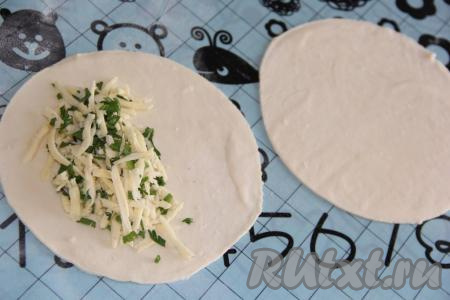 На столе, присыпанном мукой, тонко раскатать тесто скалкой, вырезать круги (диаметр, примерно, 18-20 см). На одну половину круга выложить начинку.