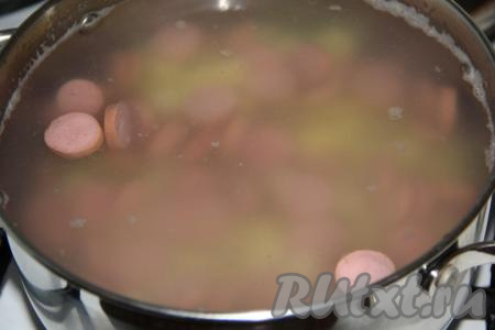 Затем сосиски нарезать на кружочки и выложить в кастрюлю с картошкой, варить 10 минут.