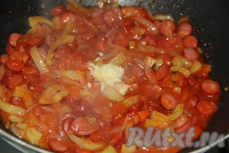 Очищенный чеснок, пропущенный через пресс, выложить на сковороду с овощами и колбасой, добавить соль и специи по вкусу, хорошо перемешать.
