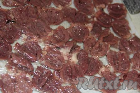 Выложить сердечки на разделочную доску, накрыть пищевой плёнкой и отбить молоточком.