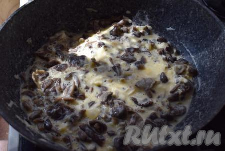 Выкладываем к начинке сметану, смешанную с яйцами. Подсаливаем по вкусу, учитывая степень солености сыра, добавляем свежемолотый перец и перемешиваем нашу начинку.