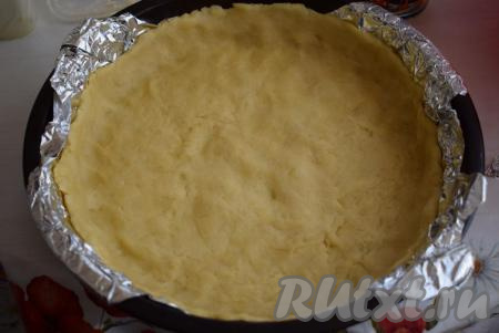 Достаем тесто из холодильника. На дно формы диаметром 24 см выкладываем фольгу или пергамент, сверху распределяем тесто, формируя бортики нашего пирога.