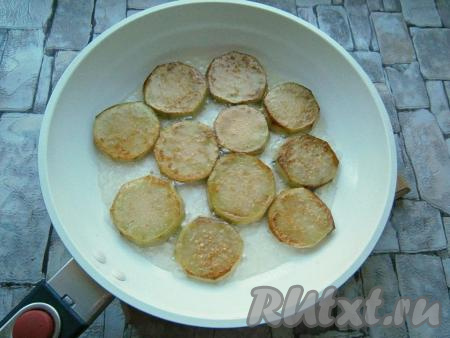 На сковороде разогреть растительное масло, выложить часть баклажанов (в один слой) и обжарить их на среднем огне до румяности с двух сторон. Обжаренные баклажаны выложить в миску, на сковороду отправить следующую порцию баклажанов, тоже обжарить их до румяности с двух сторон  и выложить в миску. Таким образом обжарить все баклажаны.