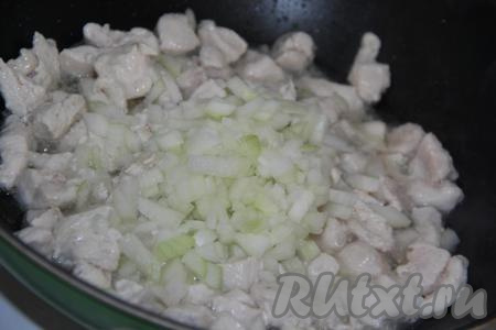 К обжаренному мясу выложить очищенный и мелко нарезанный лук. Обжаривать куриное филе с луком в течение минут 5 на среднем огне, иногда помешивая.