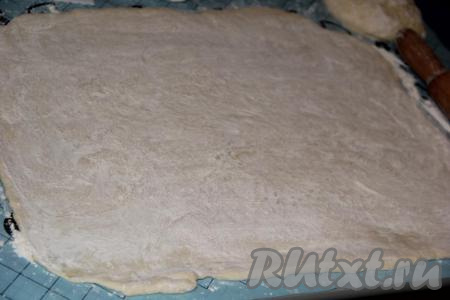 На столе, присыпанном мукой, раскатать тесто в прямоугольный пласт, он получится довольно большим, практически в половину кухонного стола.