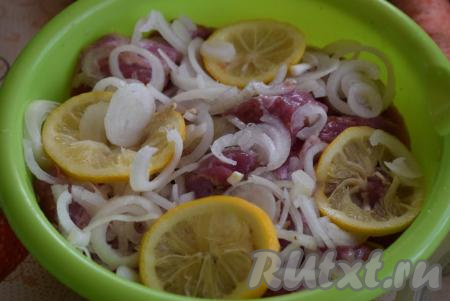 Лук и дольки лимона слегка пожмем руками, для того что бы они пустили сок, и выложим их к мясу. 