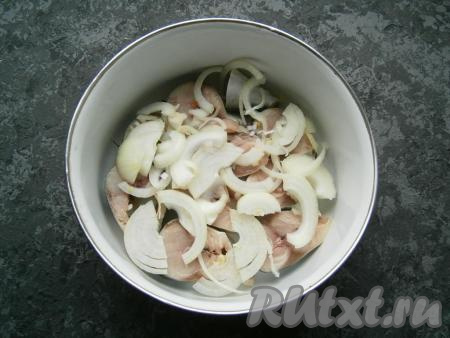 Лук нарезать тонкими полукольцами, выложить его сверху рыбы вместе с кусочками чеснока.