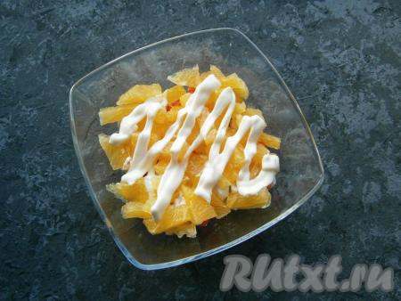 Апельсин очистить от кожуры и белых пленок, нарезать небольшими кусочками, выложить вторым слоем, нанести сеточку из майонеза.
