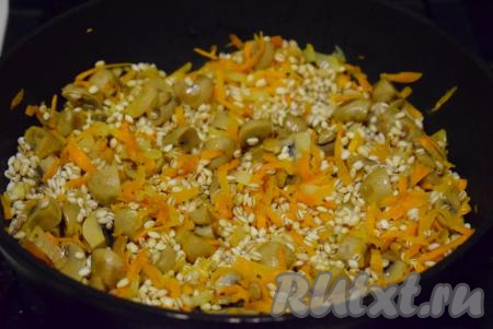С перловой крупы сливаем воду, в которой перловка замачивалась. В сковороду к тушеным овощам и шампиньонам выкладываем разбухшую перловую крупу.