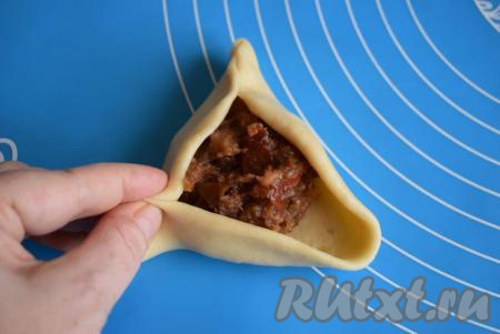 Далее можно лепить обычные закрытые пирожки, а можно сделать открытые, как сделала я. Для этого сначала защипнем тесто с одной стороны, затем получившуюся заготовку защипываем снизу с двух сторон, образуя открытый в центре треугольник.