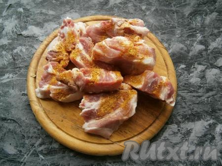 Ребрышки нарезать на части, разрезав их по кости, посыпать специями и солью.