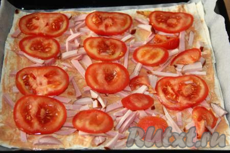 Поверх колбаски разложить кружочки помидора.