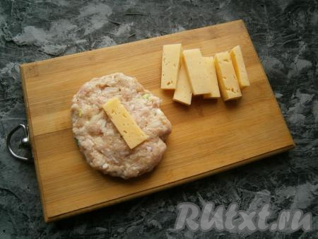 Куриный фарш тщательно перемешать. Влажными руками из части куриного фарша сформировать лепешку, в середину выложить ломтик сыра.