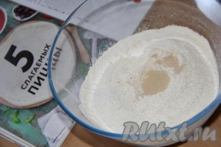 В муку, просеянную в глубокую миску, всыпать дрожжи, соль и сахар. Хорошо перемешать сухие ингредиенты, затем влить масло и воду. Воду нужно использовать тёплую, примерно, 39 градусов.