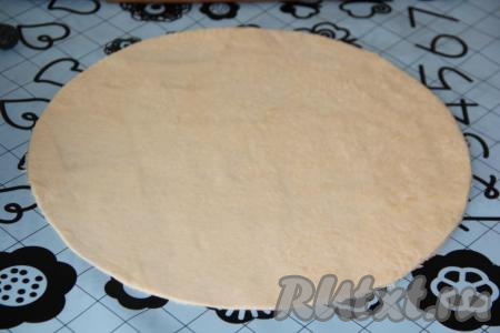 По прошествии 1-1,5 часов дрожжевое тесто хорошо поднимется, его нужно обмять и разделить на две части (в итоге у нас получатся две пиццы с морепродуктами). Оставить тесто на столе под полотенцем на 15 минут. Затем одну часть теста раскатать в тонкий круг. Я раскатала тонко тесто, а затем вырезала ножом ровный круг, используя тарелку.