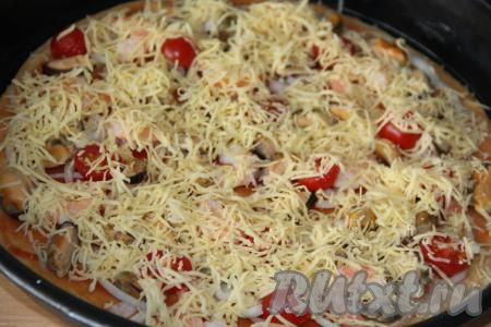 Пиццу щедро посыпать натёртым сыром и отправить в разогретую духовку. Выпекать пиццу с морепродуктами минут 8-10 при температуре 220 градусов.