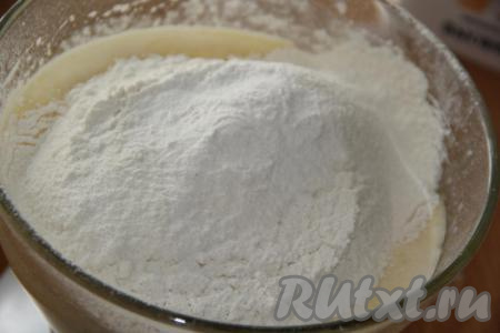 Всыпать разрыхлитель, начать частями добавлять муку, каждый раз тщательно вмешивая её столовой ложкой (или лопаткой). Муки, в зависимости от величины яиц и жирности кефира, может потребоваться немного больше или меньше. Тесто должно получиться в меру густым, воздушным, напоминающим сметану средней жирности.