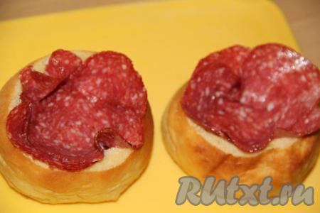 Выложить дно и бока булочек тонкими ломтиками колбасы.