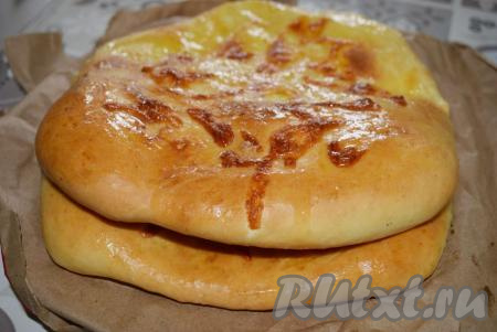Готовые хачапури с сырной начинкой станут золотисто-румяного цвета. Достаём их из духовки и смазываем кусочком сливочного масла.
